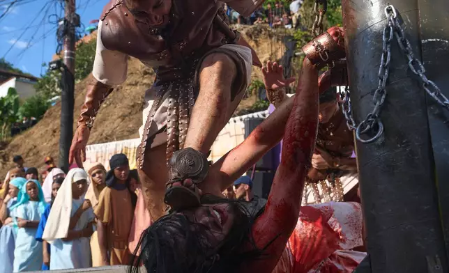 A devotee dressed as a Roman soldier places his foot on the face of a penitent depicting the role of Jesus Christ during a Way of the Cross reenactment as part of Holy Week celebrations in the Petare neighborhood in Caracas, Venezuela, Good Friday, April 3, 2026. (AP Photo/Ariana Cubillos)