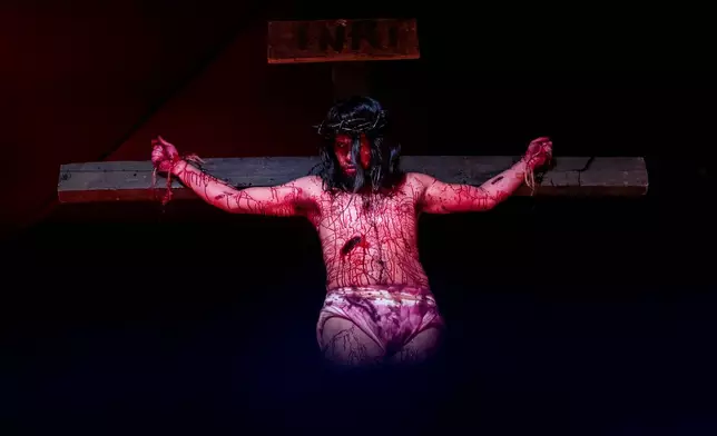 Luiz Henrique, playing the role of Jesus Christ, hangs on a cross during a Way of the Cross reenactment as part of Holy Week celebrations, at the Complexo do Alemao favela in Rio de Janeiro, Brazil, on Good Friday, April 3, 2026. (AP Photo/Bruna Prado)