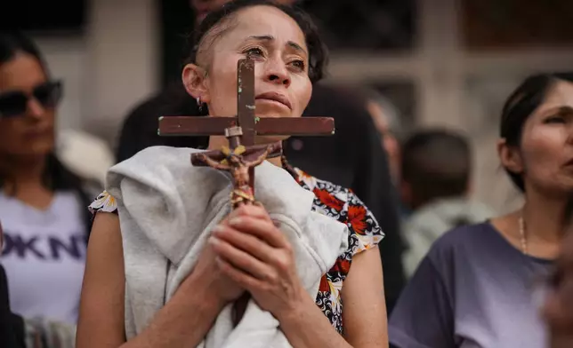 A devotee holds a cross during a Good Friday procession in the Ciudad Bolivar neighborhood of Bogota, Colombia, Friday, April 3, 2026. (AP Photo/Ivan Valencia)