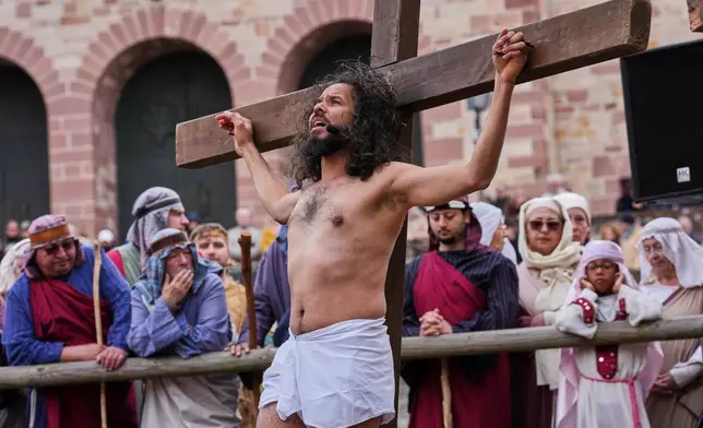 An amateur actor performing as Jesus is fixed on a cross during the traditional Good Friday procession organised by the Italian community in Bensheim, Germany, Friday, April 3, 2026. (AP Photo/Michael Probst)