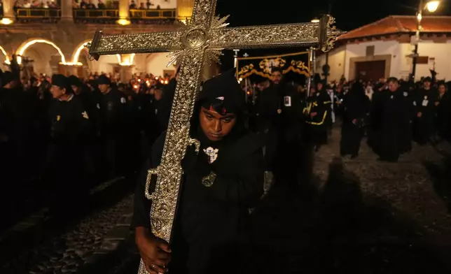 A worshiper holds a cross during La Escuela de Cristo church's Good Friday procession during Holy Week in Antigua, Guatemala, Friday, April 3, 2026. (AP Photo/Moises Castillo)