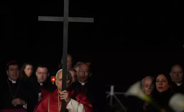 Pope Leo XIV carries a lightweight, 1.5-meter (5-foot) wooden cross during the Via Crucis, the torchlit Good Friday Stations of the Cross procession at the Colosseum in Rome, Friday, April 3, 2026, which symbolically retraces Jesus Christ's steps to his crucifixion on Calvary in Jerusalem. (AP Photo/Gregorio Borgia)