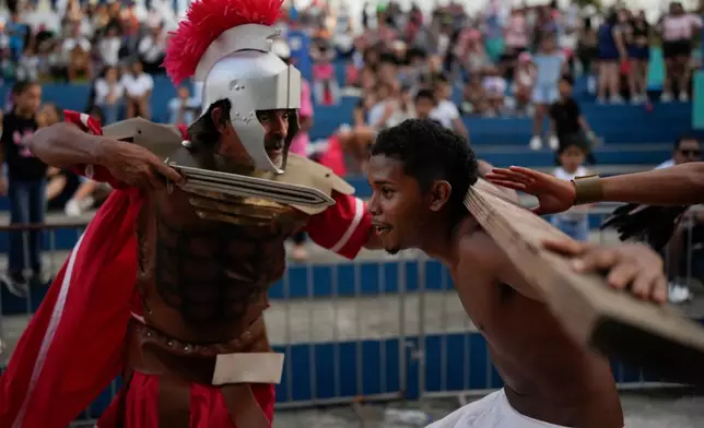 A devotee dressed as a Roman soldier assaults a penitent playing the role of one of two thieves sentenced to be crucified alongside Jesus Christ, during a Way of the Cross reenactment in Arraijan, Panama, Good Friday, April 3, 2026. (AP Photo/Matias Delacroix)