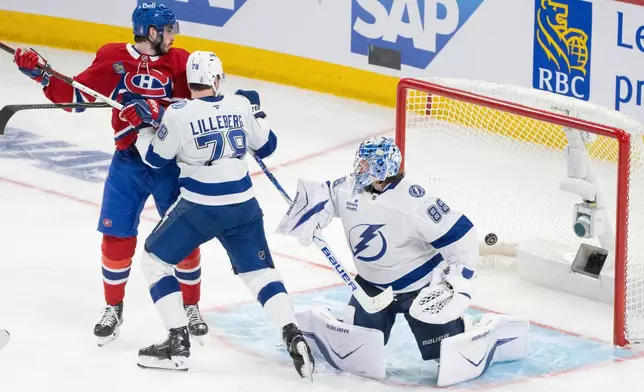 Montreal Canadiens' Kirby Dach, left, and Tampa Bay Lightning's Emil Lilleberg (78) look on as Lightning goaltender Andrei Vasilevskiy (88) is scored against by Canadiens' Lane Hutson during overtime of Game 3 in a first-round NHL hockey Stanley Cup playoff series in Montreal, Friday, April 24, 2026. (Christinne Muschi/The Canadian Press via AP)