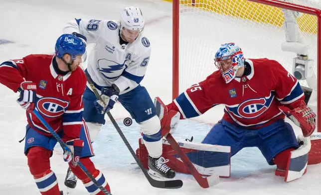 Montreal Canadiens goaltender Jakub Dobes (75) makes a save as Tampa Bay Lightning's Jake Guentzel (59) battles for the rebound against Canadiens' Mike Matheson (8) during the first period of Game 3 in a first-round NHL hockey Stanley Cup playoff series in Montreal, Friday, April 24, 2026. (Christinne Muschi/The Canadian Press via AP)