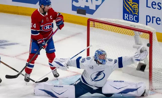 Tampa Bay Lightning goaltender Andrei Vasilevskiy (88) makes a save as Montreal Canadiens' Nick Suzuki (14) looks on during the second period of an NHL playoff hockey game in Montreal, Friday, April 24, 2026. (Christinne Muschi/The Canadian Press via AP)