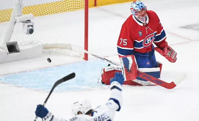 Tampa Bay Lightning's Brandon Hagel, bottom, celebrates after a goal by teammate Brayden Point against Montreal Canadiens goaltender Jakub Dobes (75) during the first period of Game 3 in a first-round NHL hockey Stanley Cup playoff series in Montreal, Friday, April 24, 2026. (Graham Hughes/The Canadian Press via AP)