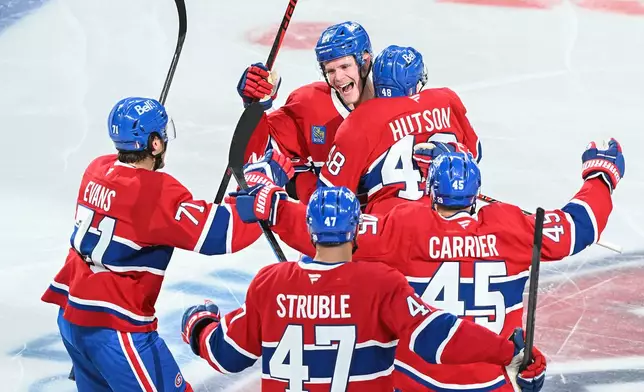 Montreal Canadiens' Lane Hutson (48) celebrates with teammate Kaiden Kuhle (21), Jake Evans (71), Jayden Struble (47) and Alexandre Carrier (45) after scoring against the Tampa Bay Lightning during overtime of Game 3 in a first-round NHL hockey Stanley Cup playoff series in Montreal, Friday, April 24, 2026. (Graham Hughes/The Canadian Press via AP)