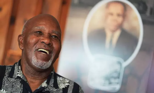 Edward Threatt, speaking in front of a photograph of his grandfather Allen Threatt Sr., is interviewed at the Threatt Filling Station along Route 66 in Luther, Okla., Wednesday, Nov. 19, 2025. (AP Photo/Julio Cortez)