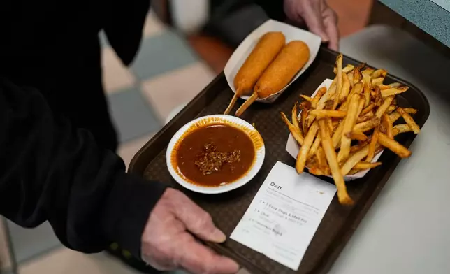 A customer picks up their order at the Cozy Dog Drive In, in Springfield, Ill., Thursday, Nov. 20, 2025. (AP Photo/Jeff Roberson)