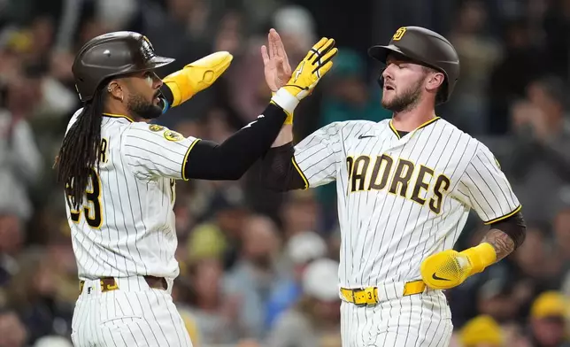 San Diego Padres' Jackson Merrill, right, and teammate Fernando Tatis Jr. celebrate after they both score off a two-RBI single by Xander Bogaerts during the third inning of a baseball game against the Seattle Mariners Tuesday, April 14, 2026, in San Diego. (AP Photo/Gregory Bull)