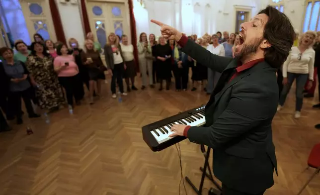Nenad Azanjac, founder of Pop Choir, leads a song during a practice in Belgrade, Serbia, Wednesday, April 15, 2026. (AP Photo/Darko Vojinovic)