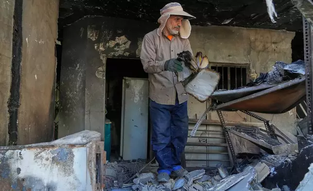 A volunteer flips a burnt book amid the debris of a residential building that, according to the authorities, was damaged on March 4 during the U.S.-Israeli military campaign, in southeastern Tehran, Iran, Tuesday, April 14, 2026. (AP Photo/Vahid Salemi)
