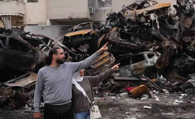 Residents gesture and point toward damage as they stand near charred cars at the site of a building destroyed in an Israeli airstrike last Wednesday in central Beirut, Lebanon, Tuesday, April 14, 2026. (AP Photo/Hassan Ammar)