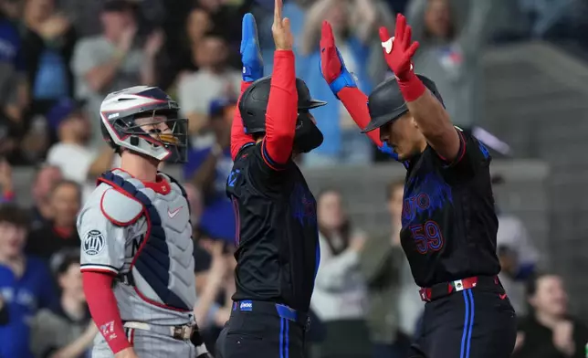 Toronto Blue Jays' Brandon Valenzuela, right, celebrates after his two-run home run with Andres Gimenez, center, in front of Minnesota Twins catcher Ryan Jeffers, left, during fourth-inning baseball game action in Toronto, Friday, April 10, 2026. (Chris Young/The Canadian Press via AP)