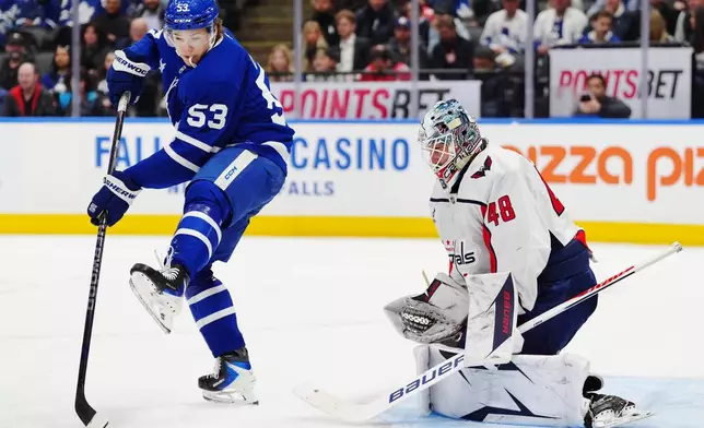 Toronto Maple Leafs' Easton Cowan (53) tries to tip the puck in front of Washington Capitals goaltender Logan Thompson (48) during second period NHL hockey action in Toronto on Wednesday, April 8, 2026. (Frank Gunn/The Canadian Press via AP)