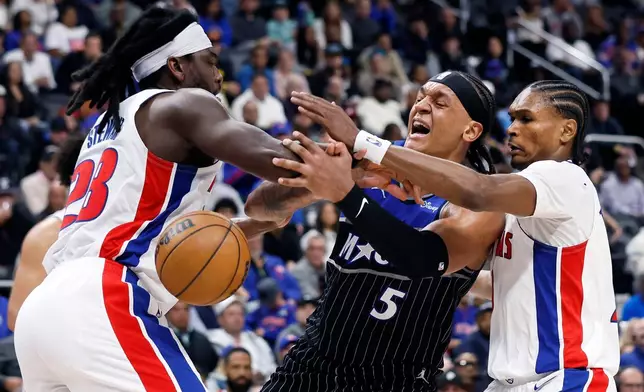 Orlando Magic forward Paolo Banchero (5) loses the ball against the defense from Detroit Pistons forward Isaiah Stewart, left, and guard Ausar Thompson, right, during the second half in Game 5 of a first-round NBA basketball playoffs series Wednesday, April 29, 2026, in Detroit. (AP Photo/Duane Burleson)