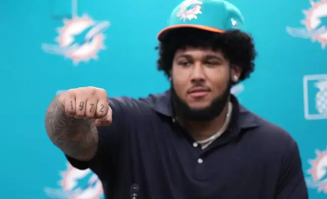Kadyn Proctor, the 12th overall pick in the NFL Draft, shows his 1972 tattoo in honor of his stepfather while being introduced to local media during a press conference, Friday, April 24, 2026, in Miami Gardens, Fla. (AP Photo/Jim Rassol)