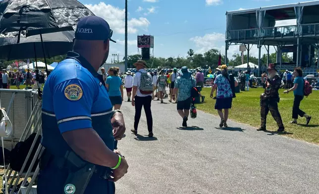 A New Orleans Police Department officer monitors a crowd on the first day of the 2026 New Orleans Jazz Heritage Festival in New Orleans on Thursday, April 23, 2026. (AP Photo/Stephen Smith)