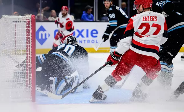 Carolina Hurricanes left wing Nikolaj Ehlers (27) looks to tip in the puck past Utah Mammoth goaltender Karel Vejmelka, left, during the first period of an NHL hockey game, Saturday, April 11, 2026, in Salt Lake City. (AP Photo/Tyler Tate)