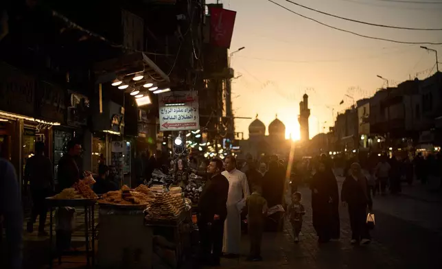 People walk at a local market near the Kadhimiya Shrine at sunset in the Shiite neighbourhood in Baghdad, Iraq, Tuesday, March 31, 2026. (AP Photo/Leo Correa)