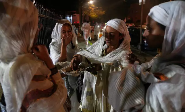 A group of women break their fast together outside of Re'ese Adbarat Debre Selam Kidist Mariam Church, an Ethiopian Orthodox Tewahedo church, in Washington, after Easter service, Sunday, April 12, 2026. (AP Photo/Jessie Wardarski)