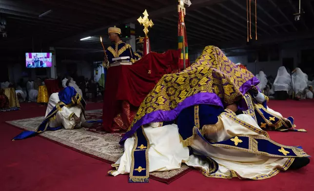 During Good Friday, priests, or "kesis," chant together as they huddle under a dark purple and gold garment, to represent Christ triumphing over evil and providing salvation, at Re'ese Adbarat Debre Selam Kidist Mariam Church, an Ethiopian Orthodox Tewahedo church, in Washington, Friday, April 10, 2026. (AP Photo/Jessie Wardarski)
