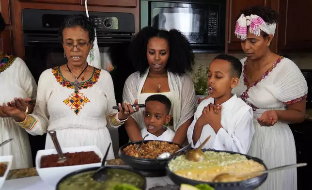 Members of the Tekola family pray together before breaking their 55-day fast on Easter Sunday, April 12, 2026, in Triangle, Va. (AP Photo/Jessie Wardarski)