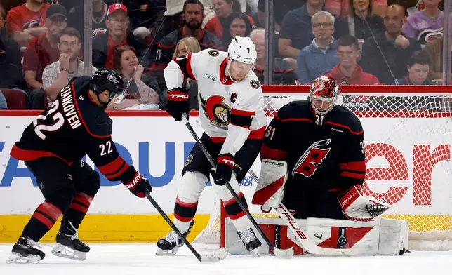 Carolina Hurricanes goaltender Frederik Andersen (31) blocks a shot by Ottawa Senators' Brady Tkachuk (7) with Hurricanes' Logan Stankoven (22) nearby during the second period of an Game 1 of an NHL hockey Stanley Cup first-round playoff series in Raleigh, N.C., Saturday, April 18, 2026. (AP Photo/Karl DeBlaker)