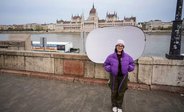 Eszter Kulisek M., 24, poses for a portrait backdropped by Parliament in Budapest, Hungary, Monday, April 13, 2026. "I hope that young people will start participating in society; that they'll be more active in politics, that they'll take on our everyday challenges." (AP Photo/Petr David Josek)