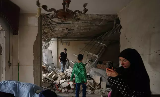 Fadi Al Zein, left, who lost both his homes in Israeli strikes in his village of Khiam and in Dahiyeh, searches through the rubble of his heavily damaged home as a child stands nearby, in Beirut's southern suburbs, Lebanon, Saturday, April 25, 2026. (AP Photo/Hassan Ammar)