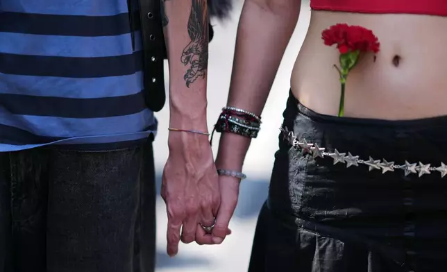 A young couple hold hands while marching with tens of thousands down Lisbon's Liberdade Avenue, Saturday, April 25, 2026, celebrating the anniversary of the April 25 1974 Carnations Revolution that restored democracy in Portugal. (AP Photo/Armando Franca)
