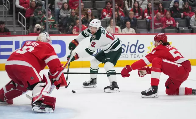 Detroit Red Wings defenseman Moritz Seider (53) defends Minnesota Wild left wing Matt Boldy (12) as he attempts to shoot on Detroit Red Wings goaltender Cam Talbot (39)in the first period of an NHL hockey game Sunday, April 5, 2026, in Detroit. (AP Photo/Paul Sancya)