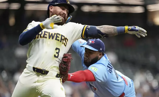 Toronto Blue Jays' Vladimir Guerrero Jr., right, tags out Milwaukee Brewers' Joey Ortiz during the eighth inning of a baseball game Tuesday, April 14, 2026, in Milwaukee. (AP Photo/Aaron Gash)