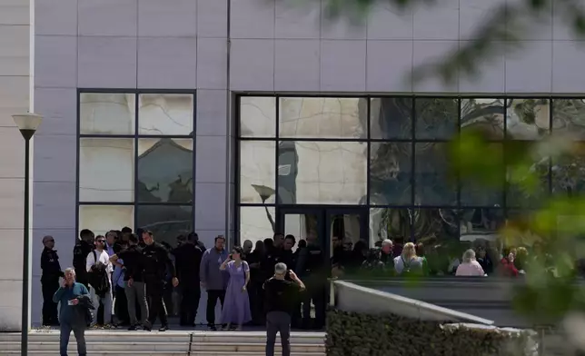 People gather outside a courthouse after a gunman opened leaving several people wounded in Athens, Tuesday, April 28, 2026. (AP Photo/Petros Giannakouris)