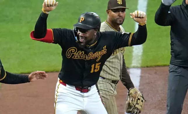 Pittsburgh Pirates' Oneil Cruz (15) celebrates in front of San Diego Padres shortstop Xander Bogaerts as he stands on third base after driving in two runs with a double off pitcher Nick Pivetta during the fifth inning of a baseball game in Pittsburgh, Tuesday, April 7, 2026. (AP Photo/Gene J. Puskar)