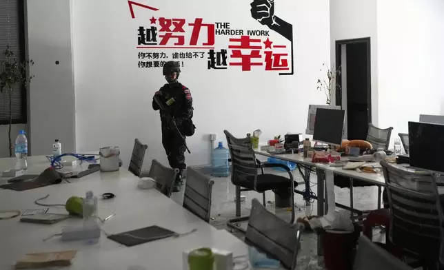 Thai soldier stand front of word motto at work station in scam compound in O'Smach, Cambodia, Tuesday, April 7, 2026. (AP Photo/Sakchai Lalit)