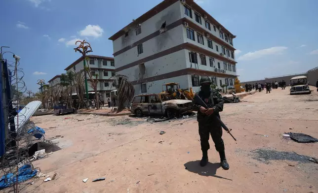 A Thai soldier guards outside the scam compound in O'Smach, Cambodia, Tuesday, April 7, 2026. (AP Photo/Sakchai Lalit)