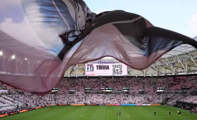 Inter Miami fans wave a flag in Nu Stadium ahead of the team's first MLS soccer match in their new stadium, against Austin FC, Saturday, April 4, 2026, in Miami. (AP Photo/Rebecca Blackwell)