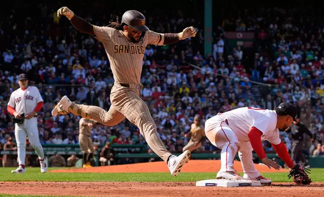 San Diego Padres' Fernando Tatis Jr., left, stretches on a force out by Boston Red Sox first baseman Willson Contreras, right, during the fifth inning of a home-opener baseball game at Fenway Park, Friday, April 3, 2026, in Boston. (AP Photo/Charles Krupa)