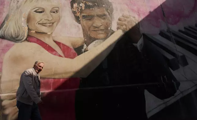 A man walks past a mural by artist Alfredo Segatori depicting late soccer legend Diego Maradona and Italian singer Raffaella Carra dancing tango, in Buenos Aires, Argentina, Monday, April 13, 2026. (AP Photo/Rodrigo Abd)