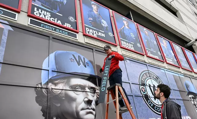 Worker set name plates along a wall for the starting lineup for the Washington Nationals' home-opener baseball game against the Los Angeles Dodgers, Friday, April 3, 2026, in Washington. (AP Photo/Terrance Williams)
