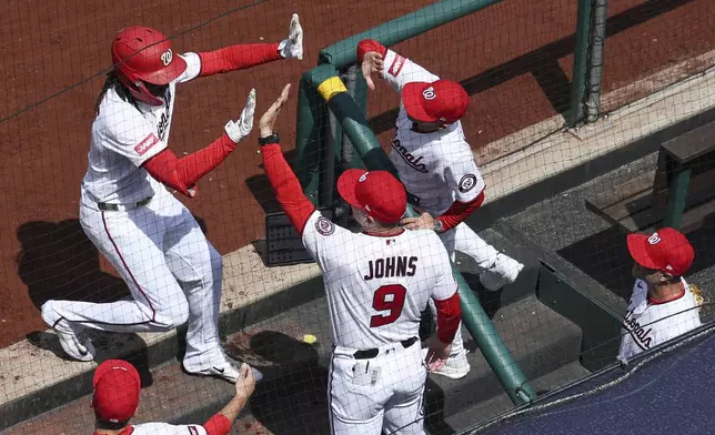 Washington Nationals' CJ Abrams, left, is greeted by teammates at the dugout after hitting a three run home run against the Los Angeles Dodgers during the first inning of an baseball game, Friday, April 3, 2026, in Washington. (AP Photo/Terrance Williams)