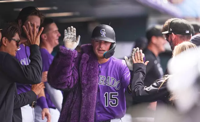 Colorado Rockies catcher Hunter Goodman, center, wears the home run coat as he is congratulated by teammates after hitting a solo home run off Houston Astros relief pitcher Enyel de Los Santos in the fourth inning of a baseball game Wednesday, April 8, 2026, in Denver. (AP Photo/David Zalubowski)