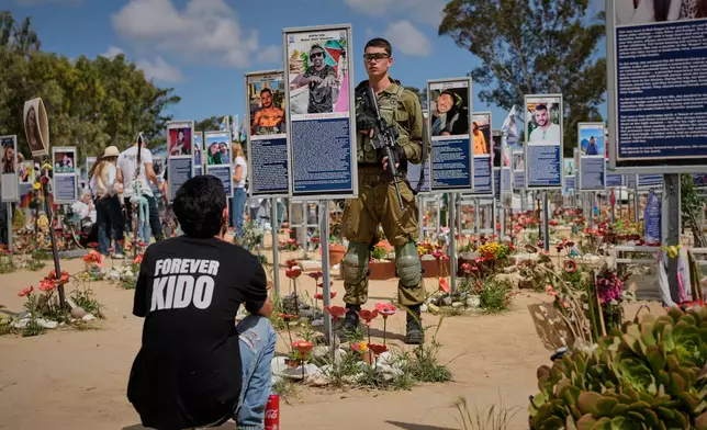Soldiers and civilians mark Israel's annual Memorial Day at the site of the Nova music festival where hundreds of revelers were killed and abducted in the Oct. 7, 2023 Hamas attack near Kibbutz Reim in southern Israel Tuesday, April 21, 2026. (AP Photo/Ohad Zwigenberg)