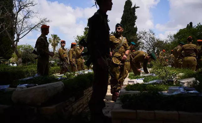 Israeli soldiers place flags and flowers on graves at a military cemetery ahead of the annual Memorial Day honoring fallen soldiers and victims of nationalistic attacks in Tel Aviv, Israel, Monday, April 20, 2026. (AP Photo/Oded Balilty)