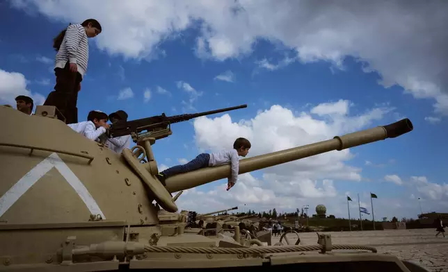 People climb on old tanks at the Armored Corps memorial site during a ceremony marking Israel's annual Memorial Day for the soldiers who died in the nation's conflicts and victims of nationalistic attacks, in Latrun, Israel, Tuesday, April 21, 2026. (AP Photo/Ariel Schalit)