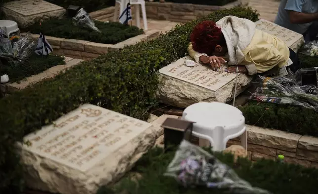 A woman weeps over the grave of her relative as Israel marks the annual Memorial Day, honoring soldiers killed in the nation's conflicts and victims of nationalistic attacks, at Mount Herzl military cemetery in Jerusalem, Tuesday, April 21, 2026. (AP Photo/Leo Correa)