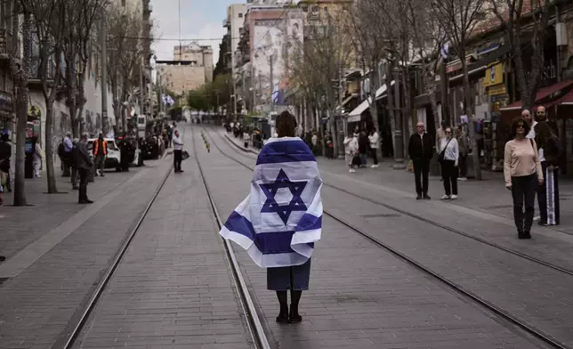 People stand still to observe two minutes of silence as air raid sirens sound, marking Israel's annual Memorial Day for the soldiers who died in the nation's conflicts and victims of nationalistic attacks, in Jerusalem, Tuesday, April 21, 2026. (AP Photo/Mahmoud illean)