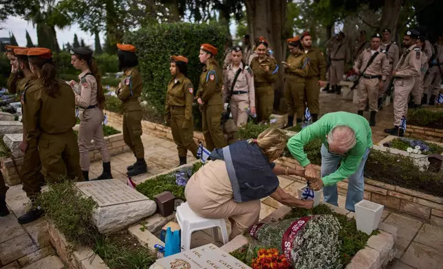 Israeli soldiers and relatives visit a military cemetery ahead of the annual Memorial Day honoring fallen soldiers and victims of nationalistic attacks in Tel Aviv, Israel, Monday, April 20, 2026. (AP Photo/Oded Balilty)